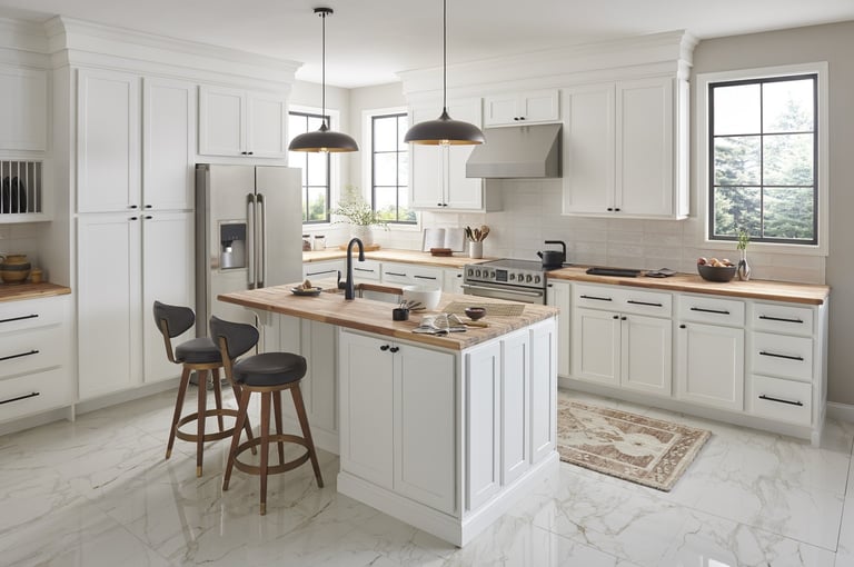 Modern white kitchen with marble countertops, wood-topped island, pendant lights, and bar seating